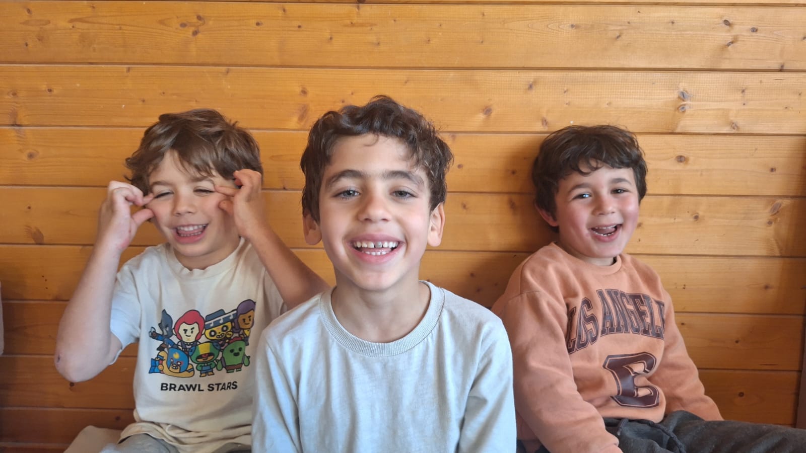 שלושה ילדים מחייכים במפגש של מעגל השבט